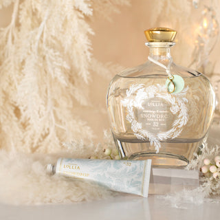 Decorative bottle with a label, white candle, and small bottle on a textured surface with blurred lights in the background.